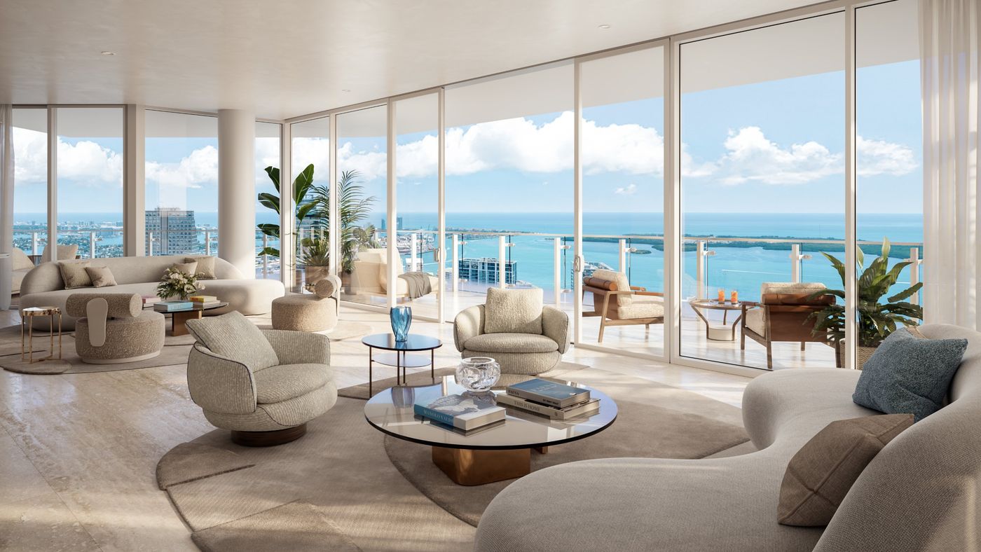 Living room with curved sofas and glass walls opening to a terrace over Biscayne Bay